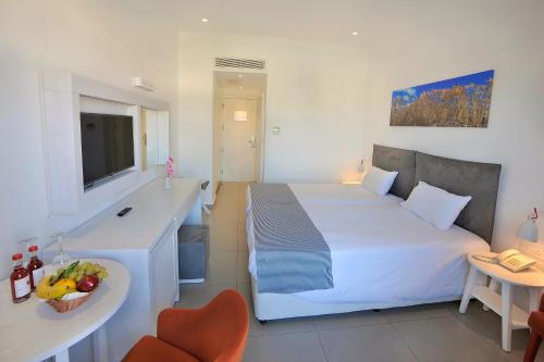 a hotel room with a large white bed and a desk at Nissiana Hotel & Bungalows in Ayia Napa