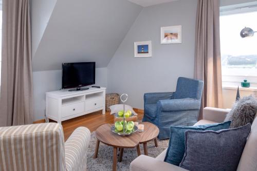 ein Wohnzimmer mit einem Sofa und einem TV in der Unterkunft Weisse Düne - App. 5 in Wenningstedt-Braderup
