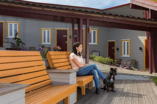 a woman sitting on a bench with a dog at Dolmsundet Hotell Hitra in Melandsjøen