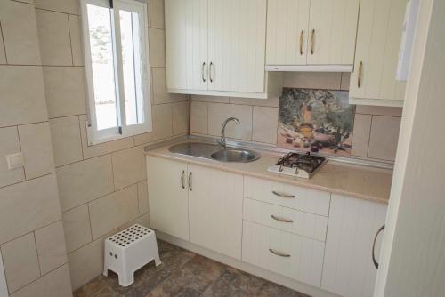 a kitchen with white cabinets and a sink and a window at Las Casas de Nani in Beas de Segura