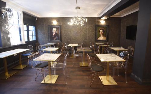 a dining room with tables and chairs and portraits on the wall at The Pack And Carriage London in London