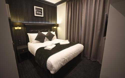 a hotel room with a bed with two towels on it at The Pack And Carriage London in London