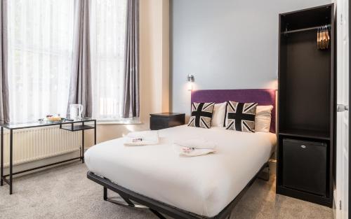 a large white bed in a room with windows at Royal London Hotel By Saba in London