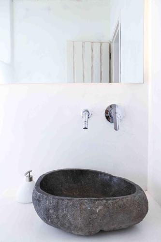 a bathroom with a stone sink and a mirror at VLIA MAR Myconian Residences in Kalafatis