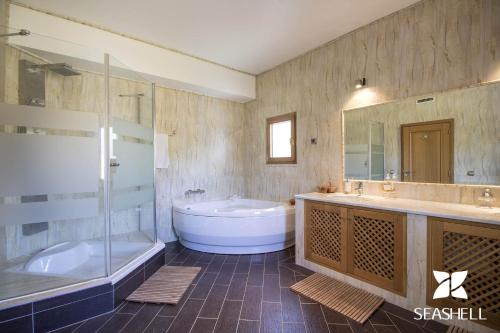 un ampio bagno con vasca, lavandino e vasca di Villa Valentina a Almancil