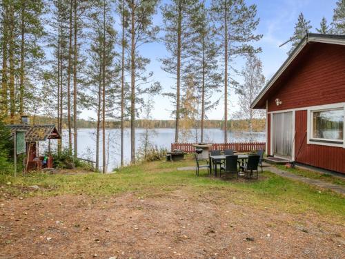 a cabin with a table and chairs next to a lake at Holiday Home Aamuntorkku by Interhome in Vuoriniemi