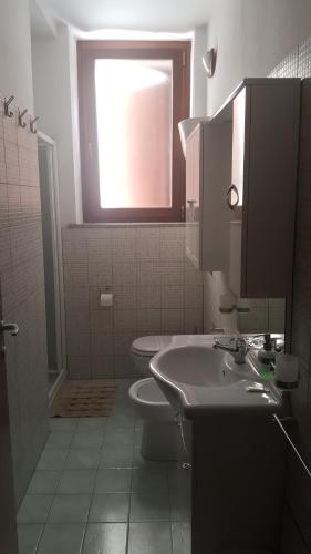 a bathroom with a sink and a toilet and a window at SERRA E MESU Affittacamere in Magomadas