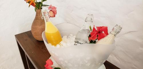 two bottles of orange juice in a white bowl on a table at A Casa de Gabriella in Itacaré