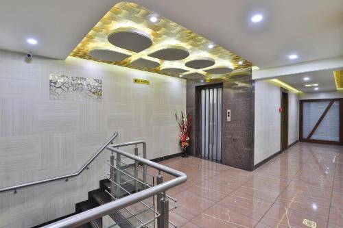 a lobby with a staircase and a ceiling at Hotel Pearl in Vadodara