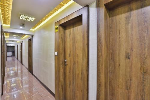 a row of wooden doors in a hallway at Hotel Pearl in Vadodara