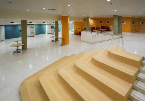 a lobby with wooden stairs in a building at UNAHOTELS Varese in Varese