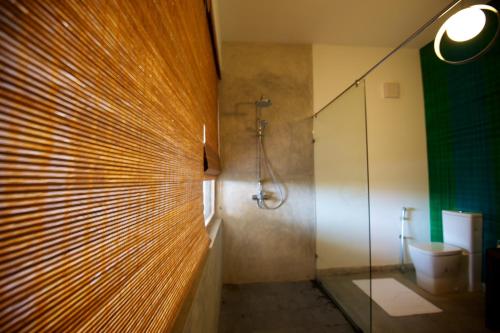 a bathroom with a glass shower and a toilet at Roman Beach Hotel in Hikkaduwa