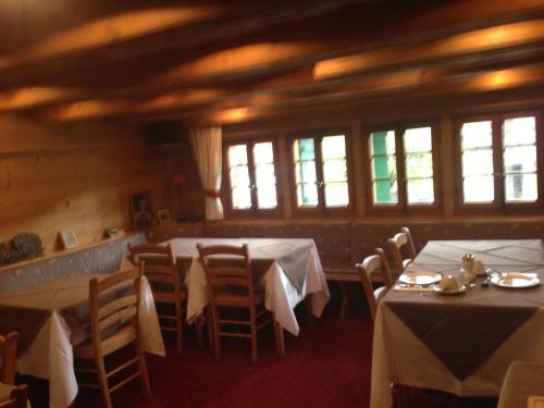 uma sala de jantar com mesas, cadeiras e janelas em Auberge de la poste em Les Diablerets