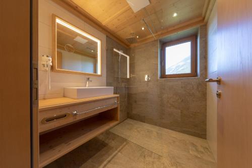 a bathroom with a sink and a mirror and a shower at Gasthof Tannen - Alm in Stummerberg
