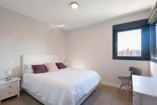 a white bedroom with a bed and a window at Playa & Golf in Alicante