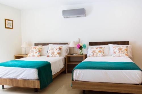 two beds in a room with two tables at Hotel Avanti Chipichape in Cali