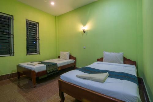 two beds in a room with green walls and windows at Relax Resort Angkor Villa in Siem Reap