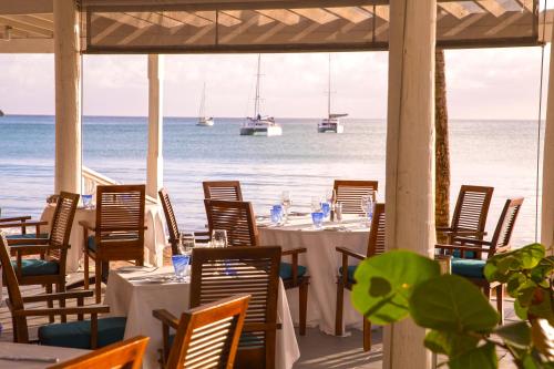 a restaurant with tables and chairs with boats in the ocean at Carlisle Bay in Old Road