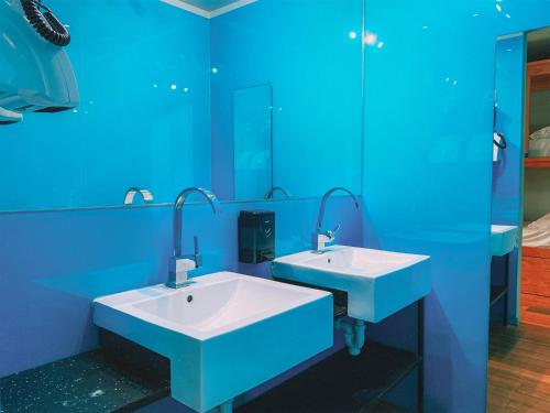 uma casa de banho azul com 2 lavatórios e um espelho em CATS Porto Hostel em Porto
