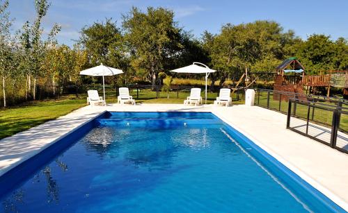 einen Pool mit Stühlen und Sonnenschirmen im Hof in der Unterkunft Cabañas Las Troncas in Merlo