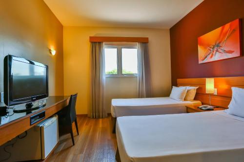 a hotel room with two beds and a flat screen tv at Nobile Inn Jundiaí in Jundiaí