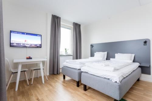 two beds in a room with a table and a tv at ApartDirect Linköping Arena in Linköping