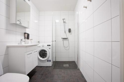 a white bathroom with a washing machine in it at ApartDirect Linköping Arena in Linköping