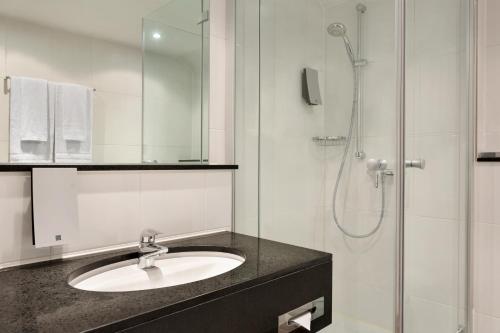 a bathroom with a sink and a shower at Ramada by Wyndham München Airport in Oberding