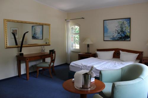 Habitación de hotel con cama, mesa y escritorio. en Landhotel Gustav, en Beelitz Heilstätten