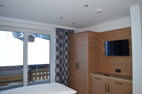 a bedroom with a bed and a tv and a window at Haus Garni Luggi Leitner in Mittelberg