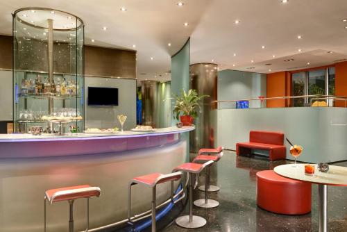 ボローニャにあるUNA Hotels Bologna Centroの赤いスツールとテーブルのあるレストランのバー
