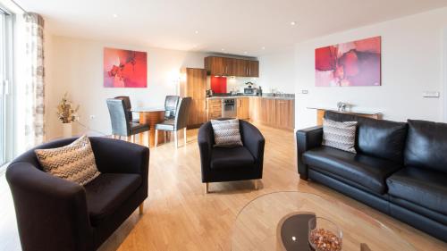sala de estar con sofá y sillas y cocina en The Spires Serviced Apartments Birmingham, en Birmingham