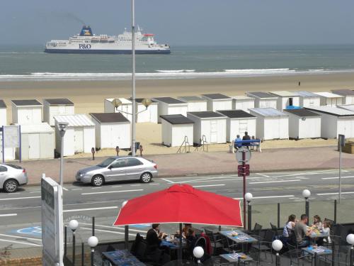 a cruise ship in the ocean and a red umbrella at Hôtel De La Plage in Calais