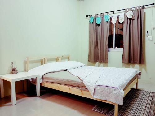 a bedroom with a bed and a table and a window at NBH.@ Prannok in Bangkok