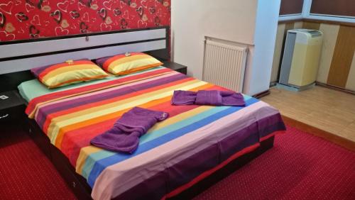 Una cama colorida con dos toallas moradas. en CoquetteHouse Gara de Nord en Bucarest