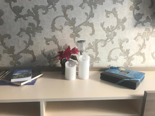 a table with two white candles and flowers on it at A Modern Suite Close to Gondola Ski Lift in Bakuriani