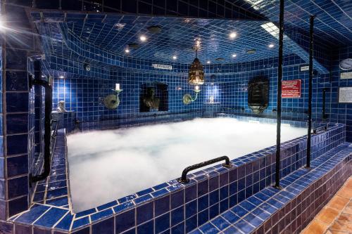 bañera en una habitación de azulejos azules con bañera en Hotell Gästis, en Varberg