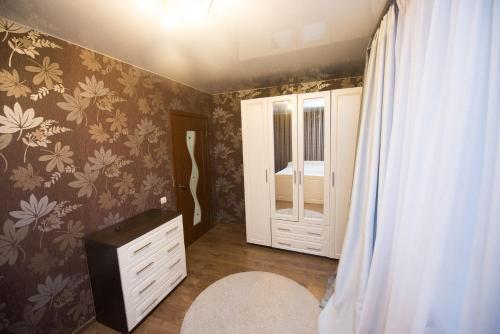 イヴァノヴォにあるАпартаменты на Шереметевскомの花柄の壁紙と白いドレッサーが備わるベッドルーム1室、