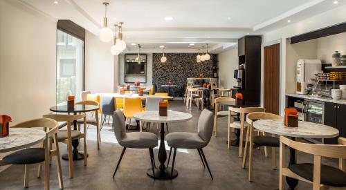 Un restaurante con mesas y sillas y una cocina. en Citadines La Défense Paris, en Courbevoie
