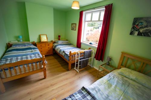 a bedroom with three beds and a window at Culsharg Cottage in Bargrennan