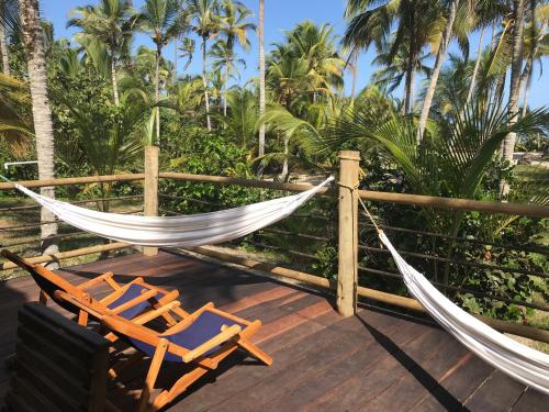 a hammock and chairs on a deck with palm trees at Playa Pikua Ecolodge in Guachaca