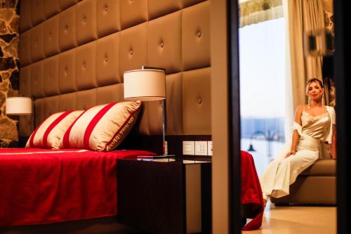 a woman sitting on a bed in a hotel room at Ngonia Bay Boutique Hotel in Milazzo
