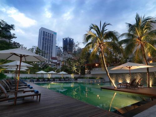 吉隆坡的住宿－迷卡薩全套房酒店，度假村内带椅子和遮阳伞的游泳池