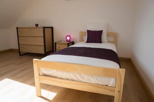 a bedroom with a wooden bed and a dresser at Gîtes de l'Orée du Bois - Boussières in Boussières