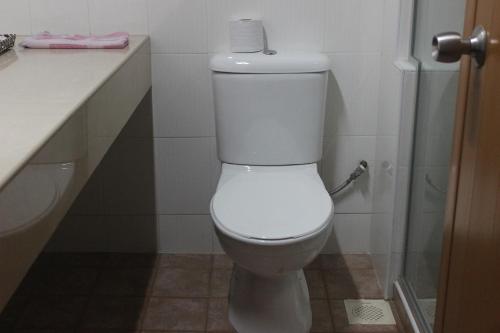 a bathroom with a toilet with a roll of toilet paper on top at Hotel Supreme in Singapore