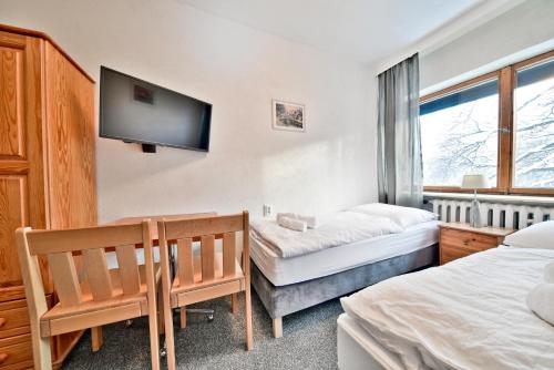 a bedroom with two beds and a flat screen tv at Panorama Gór w Karpaczu in Karpacz