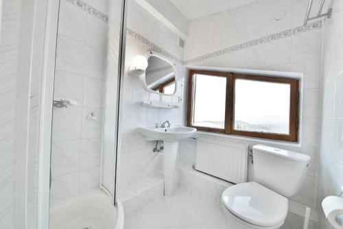 a white bathroom with a toilet and a sink at Panorama Gór w Karpaczu in Karpacz