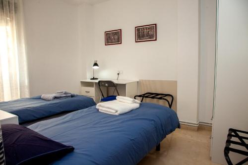 1 dormitorio con 2 camas con sábanas azules y escritorio en IMPECABLE APARTAMENTO EN EL CENTRO DE GRANADA, en Granada
