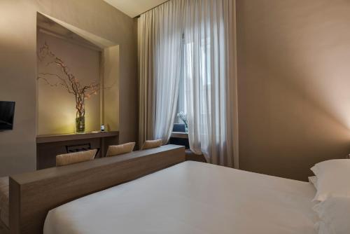a bedroom with a large white bed and a mirror at Hotel dei Barbieri in Rome
