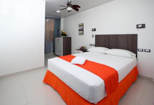 ein Schlafzimmer mit einem großen Bett mit einer orangefarbenen Decke in der Unterkunft Hotel Milan Costa Rica in San José